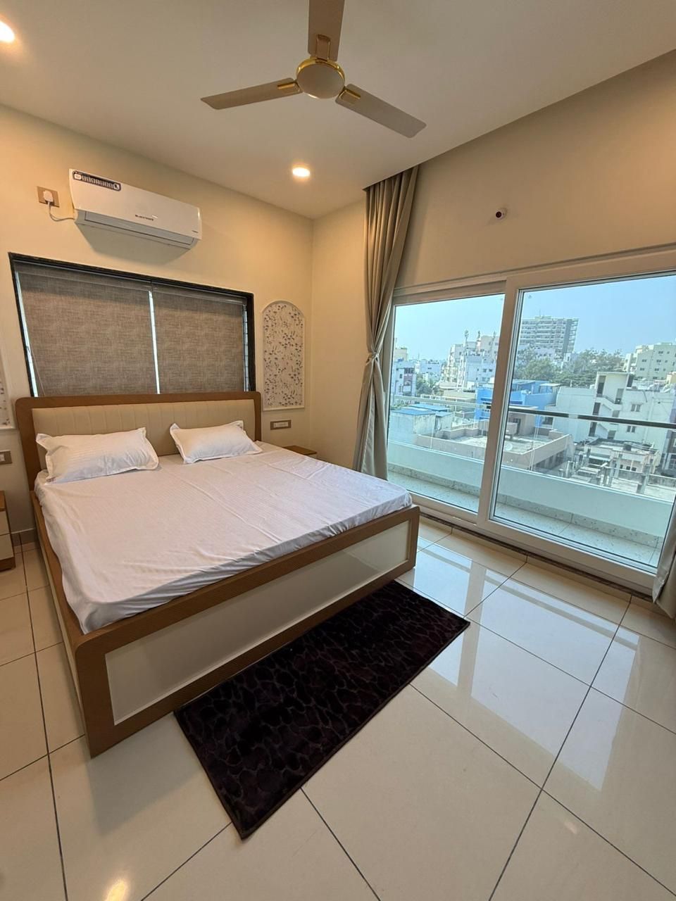 Air-conditioned bedroom with a double bed and a balcony door at Zuza Homes, Hyderabad